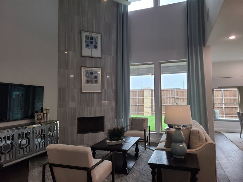 A chic living room with floor-to-ceiling tiled fireplace, elegant seating, and large windows.