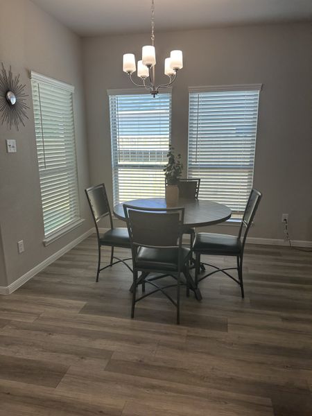 A cozy dining area with a round table, elegant chandelier, and large windows enhancing natural light. A cozy dining area with a round table, elegant chandelier, and large windows enhancing natural light.