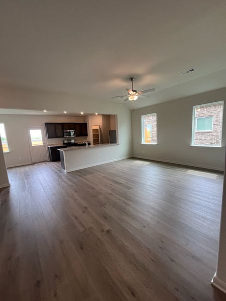 An open living space with sleek hardwood floors, recessed lighting, and a modern kitchen, perfect for gatherings.