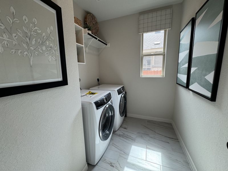 A bright laundry room with modern appliances, elegant artwork, and a window letting in natural light. A bright laundry room with modern appliances, elegant artwork, and a window letting in natural light.