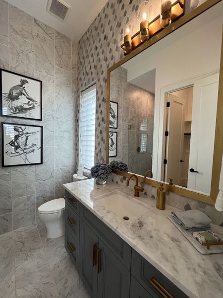 Elegant bathroom with marble surfaces, gold fixtures, and artistic decor, offering a luxurious and stylish ambiance.