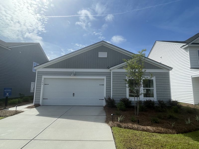 A charming single-story home with gray siding and a manicured yard in Cypress Preserve: American Dream Series by Lennar (Moncks Corner, SC).