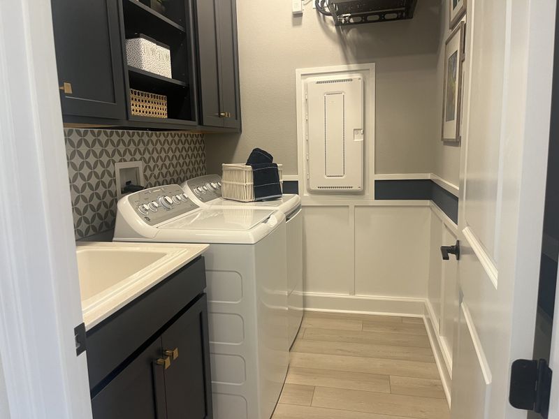 A modern laundry room with sleek cabinets, patterned backsplash, and a washer-dryer set. A modern laundry room with sleek cabinets, patterned backsplash, and a washer-dryer set.