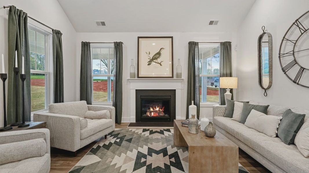 Green accented, inviting family room with large windows, vaulted ceilings, and fireplace at Pinebrook by DRB Homes Green accented, inviting family room with large windows, vaulted ceilings, and fireplace at Pinebrook by DRB Homes