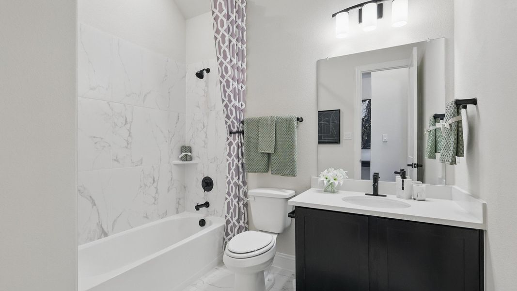 Indulge in elegance with marble tile features and sleek black fixtures in this Green Oaks Preserve bathroom. Indulge in elegance with marble tile features and sleek black fixtures in this Green Oaks Preserve bathroom.