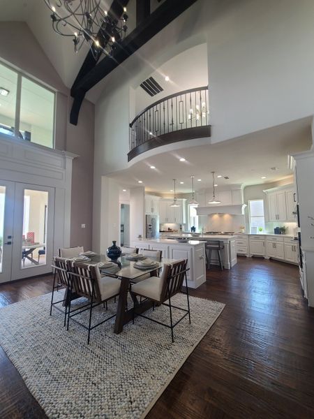 A spacious kitchen and dining area featuring high ceilings, wood flooring, and a modern chandelier. A spacious kitchen and dining area featuring high ceilings, wood flooring, and a modern chandelier.