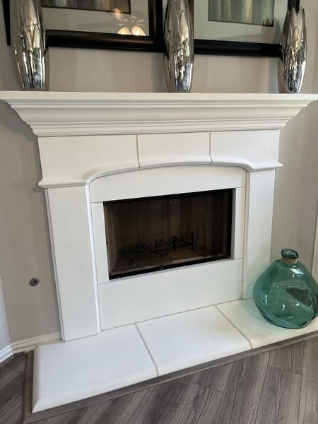 A chic interior fireplace with a sleek white mantel, decorative accents, and elegant flooring. A chic interior fireplace with a sleek white mantel, decorative accents, and elegant flooring.
