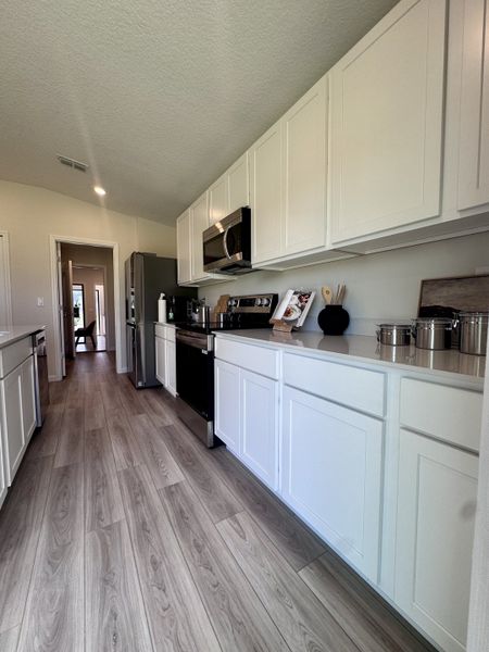 A sleek kitchen featuring white cabinetry, modern appliances, and light wood flooring for a clean, contemporary feel.