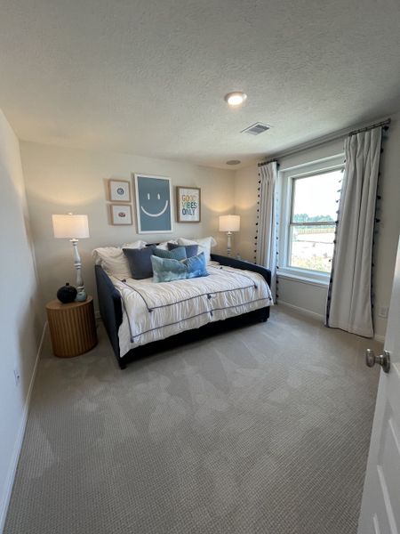 Cozy bedroom with a daybed, stylish art, and natural light through large windows dressed with drapes.