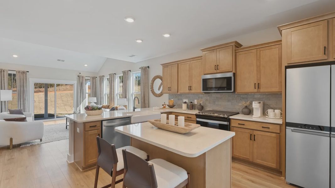 Large, open concept warm toned kitchen with Whirpool appliances, counterstools, and quartz countertops in Spartanburg, SC