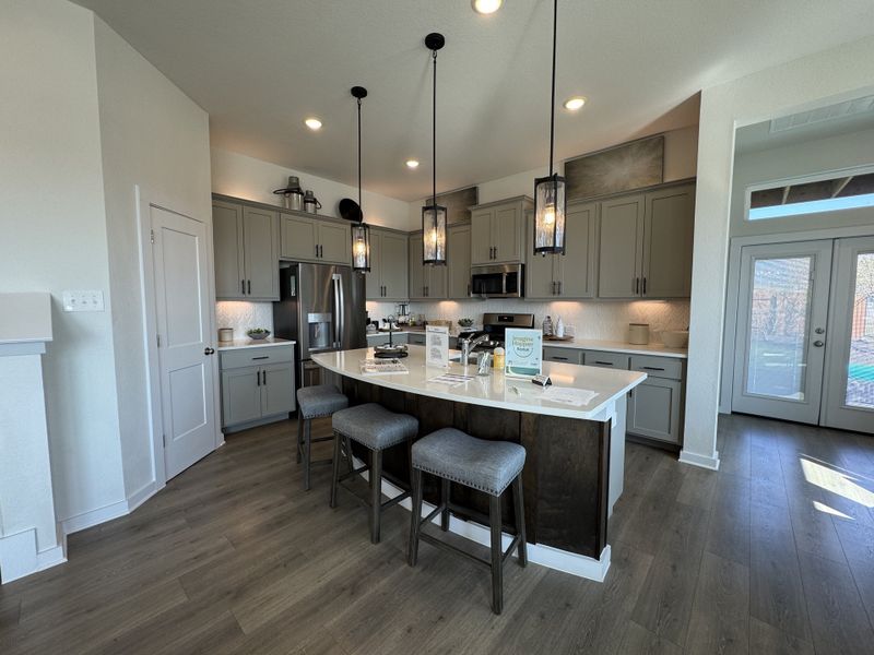 A modern kitchen with a central island, sleek gray cabinets, and pendant lighting, featuring stainless steel appliances. A modern kitchen with a central island, sleek gray cabinets, and pendant lighting, featuring stainless steel appliances.