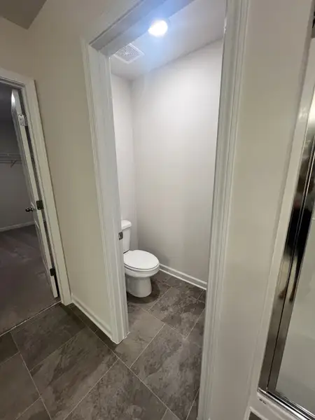A sleek bathroom space with a modern toilet, neutral walls, and stylish gray tile flooring.