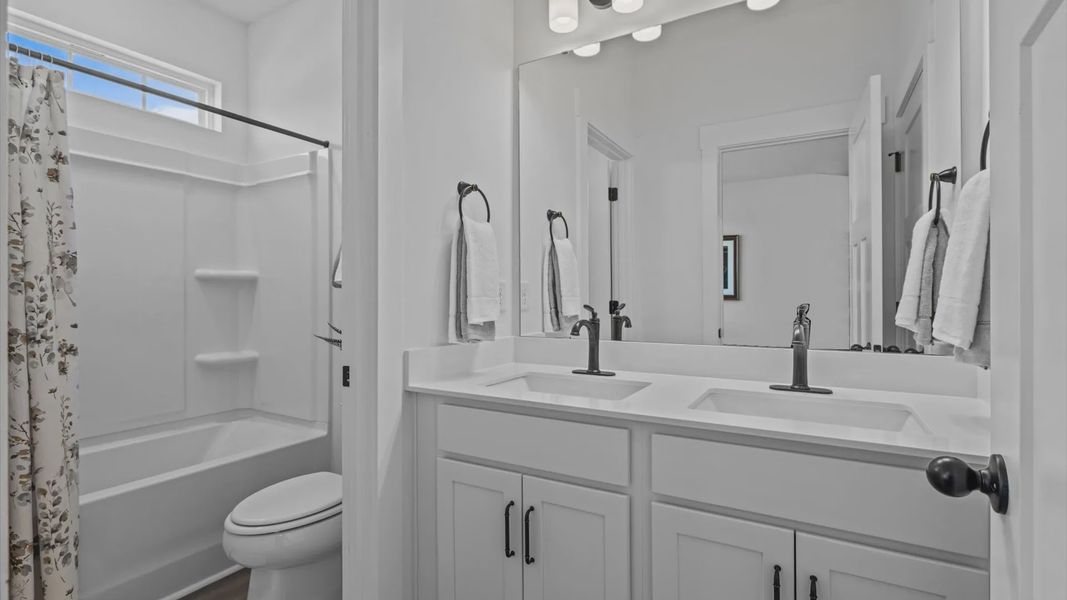 Double sink vanity with white cabinetry and black accents in secondary bathroom at Pinebrook by DRB Homes in Woodruff, SC Double sink vanity with white cabinetry and black accents in secondary bathroom at Pinebrook by DRB Homes in Woodruff, SC