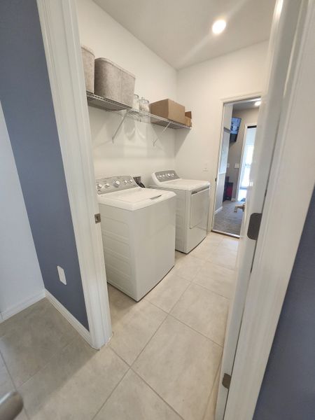 A functional laundry room featuring a modern washer and dryer, with practical shelving for storage and organization.