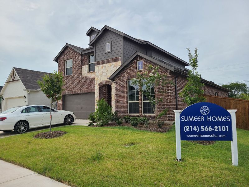 A charming brick home with a stone accent and manicured lawn in Courts Of Bonnie Brae by Sumeer Homes, Denton, TX.