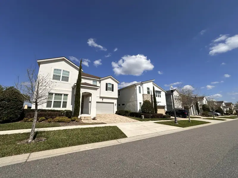 A modern two-story home with neutral tones and lush landscaping in Solara Resort by Mattamy Homes (Kissimmee, FL).