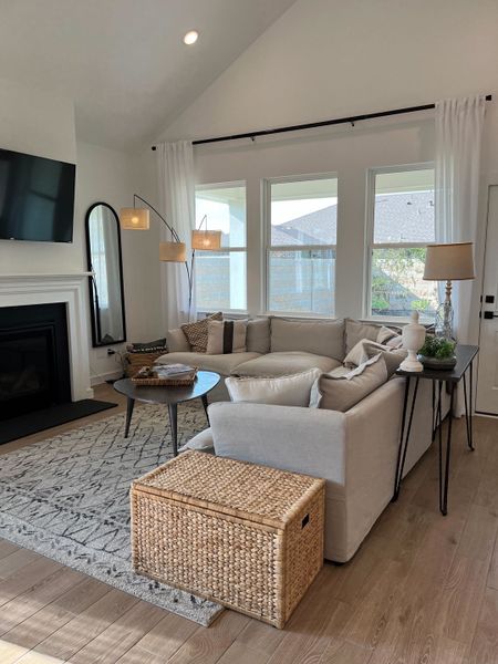 A cozy living room featuring a sectional sofa, modern decor, and a fireplace, with soft natural lighting from large windows.