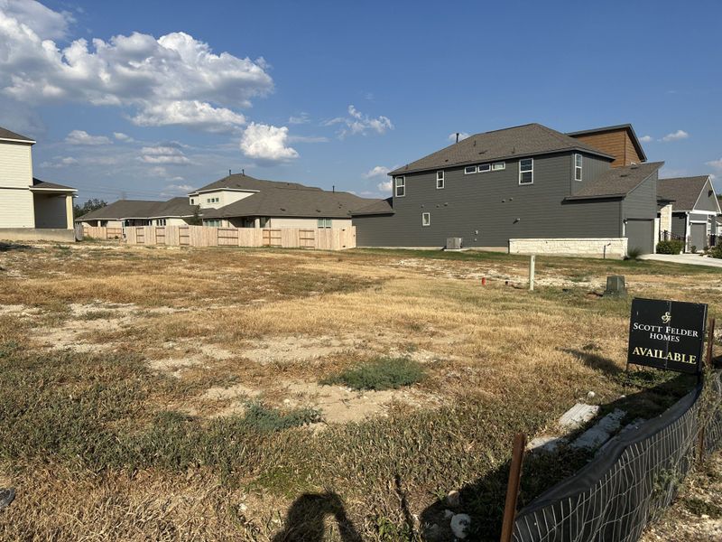 Spacious lot in Park Hill Commons by Scott Felder Homes, San Antonio, TX, surrounded by modern homes and clear blue skies.