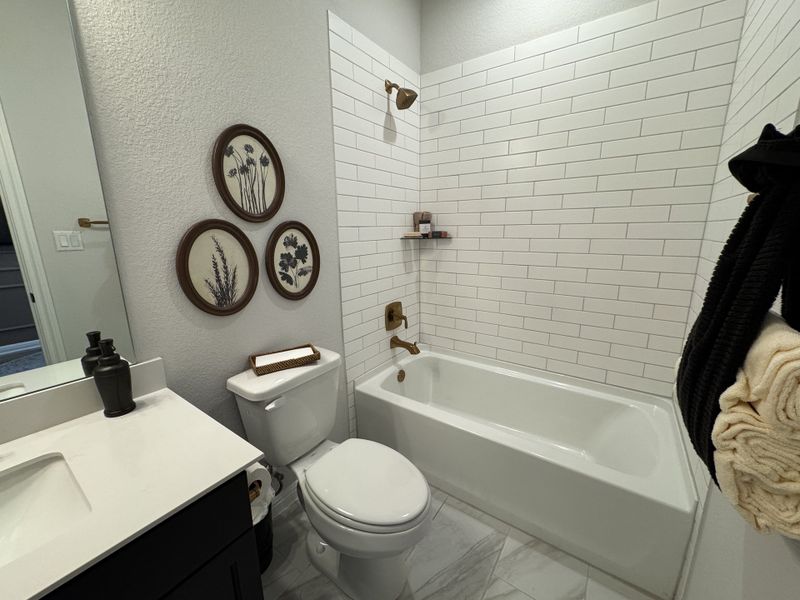 A contemporary bathroom with white subway tiles, elegant bronze fixtures, and botanical wall art. A contemporary bathroom with white subway tiles, elegant bronze fixtures, and botanical wall art.