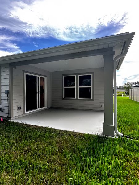A modern home with a covered patio and lush lawn in Anabelle Island - Executive Series by KB Home (Green Cove Springs, FL).