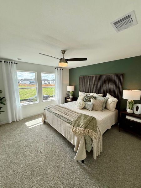 A cozy bedroom with a stylish wood headboard, plush bedding, and natural light streaming in through large windows.