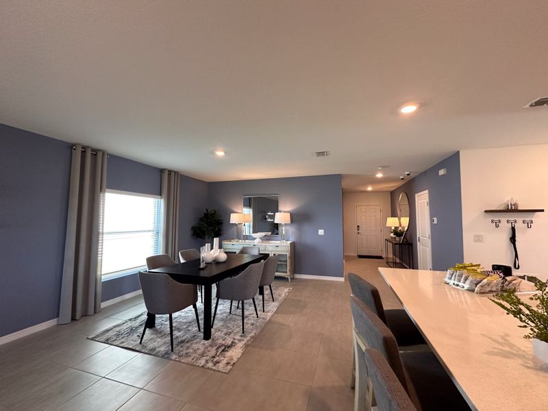 A modern dining area with a sleek black table, gray chairs, and elegant decor, accentuated by soft blue walls and stylish lighting.