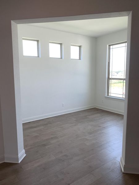 A bright room with elegant wood flooring and three high windows adding a modern touch. A bright room with elegant wood flooring and three high windows adding a modern touch.