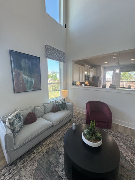 A chic living area with a high ceiling, gray sofa, burgundy chair, and contemporary decor.
