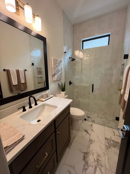 A sleek bathroom with marble flooring, a frameless glass shower, and elegant vanity lighting. A sleek bathroom with marble flooring, a frameless glass shower, and elegant vanity lighting.