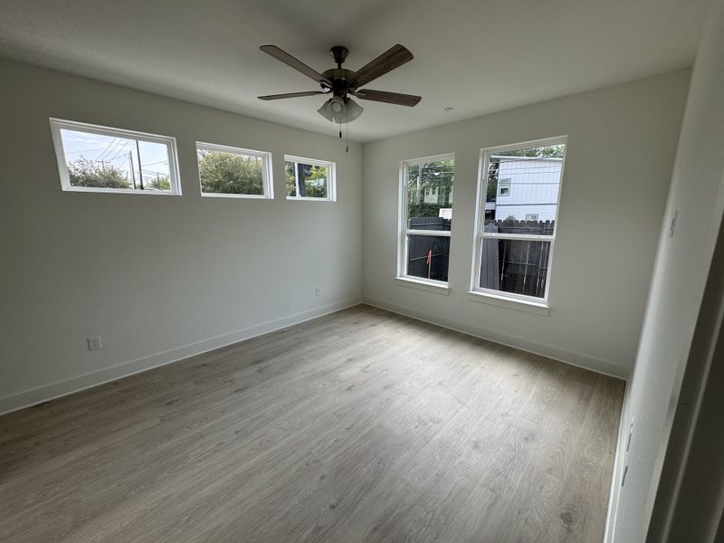 A bright room with wood floors, large windows, and a ceiling fan. Perfect for relaxing and entertaining.
