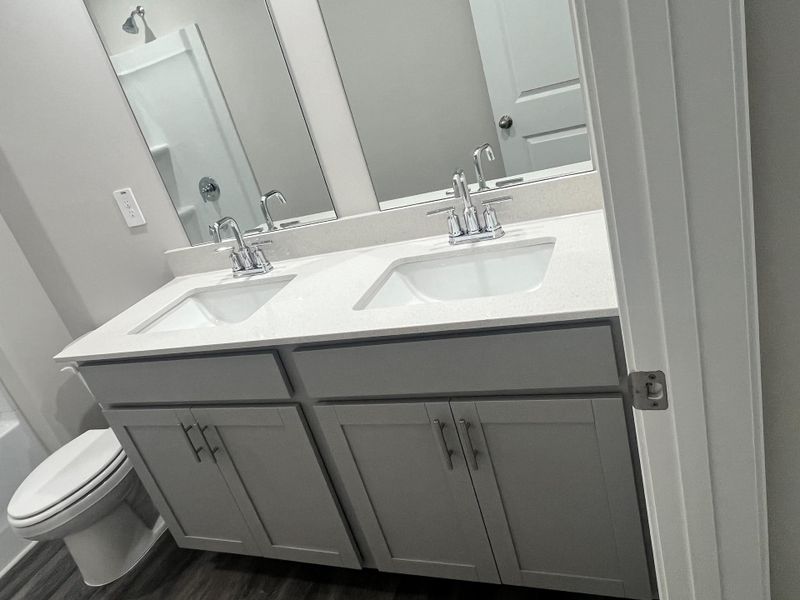 A modern bathroom featuring a dual sink vanity, sleek chrome faucets, and soft gray cabinetry. A modern bathroom featuring a dual sink vanity, sleek chrome faucets, and soft gray cabinetry.