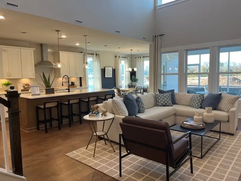 A spacious open-concept living area with a cozy sectional, sleek kitchen, and large windows creating a bright ambiance.