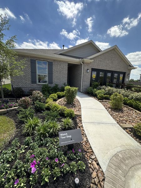 A charming brick home with landscaped garden and paved path in Oakwood Trails by KB Home (Tomball, TX).