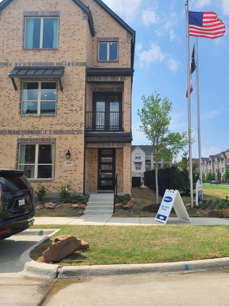 Charming brick home with a sleek facade and manicured lawn in Wade Settlement by Megatel Homes (Frisco, TX).