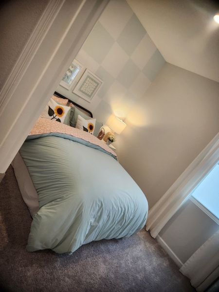A cozy bedroom with pastel decor, sunflower accents, plush carpeting, and soft lighting for a welcoming atmosphere.