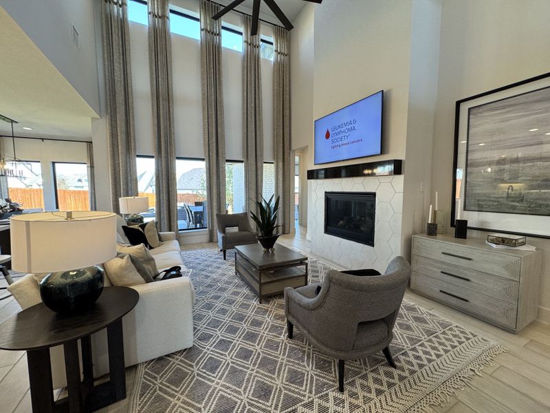 A modern living room with high ceilings, floor-to-ceiling windows, cozy seating, and elegant decor.