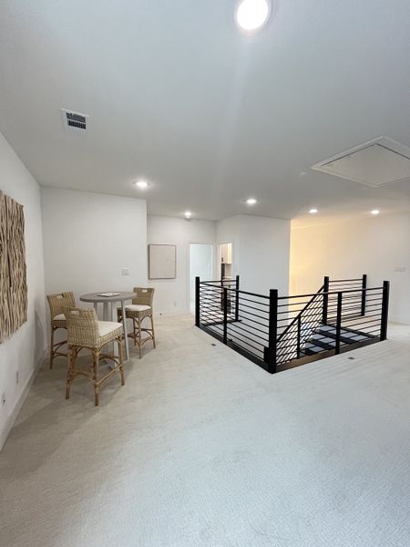A spacious loft with plush carpet, a chic bistro table, and modern railing offers a cozy retreat upstairs. A spacious loft with plush carpet, a chic bistro table, and modern railing offers a cozy retreat upstairs.