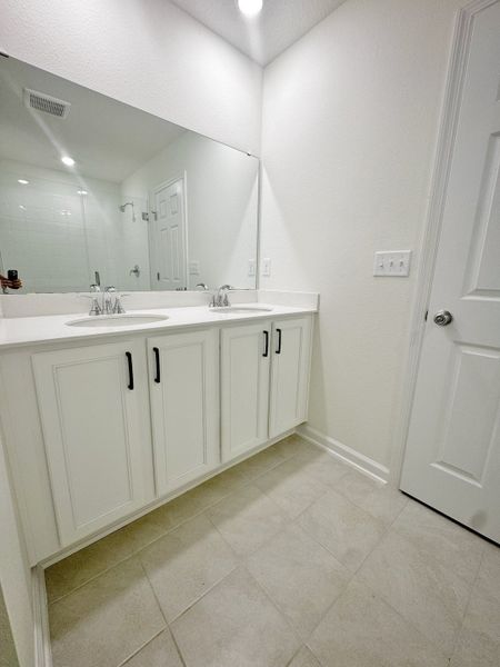 Elegant bathroom with dual sinks, large mirror, and sleek white cabinetry for a clean, modern look.