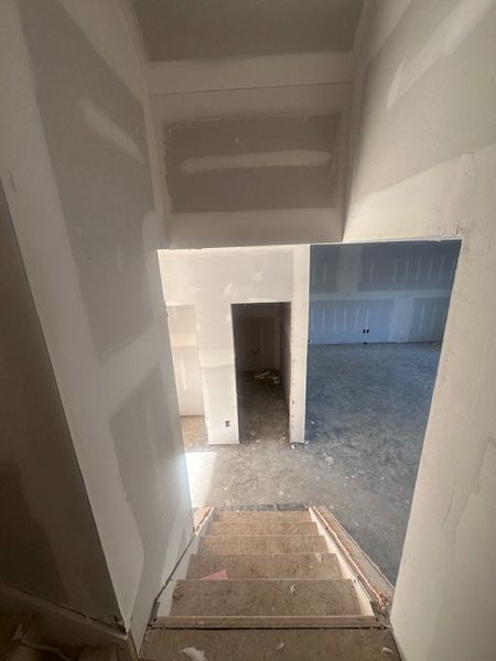 A staircase leading to an unfinished basement with drywall and an open space.