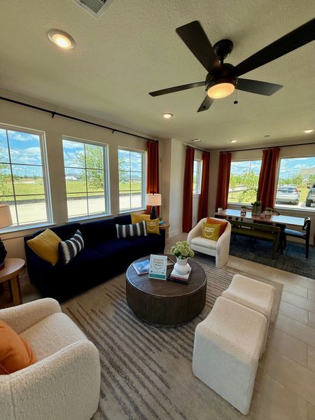 A cozy living space with a navy sofa, neutral armchairs, and modern decor, featuring large windows and a ceiling fan. A cozy living space with a navy sofa, neutral armchairs, and modern decor, featuring large windows and a ceiling fan.