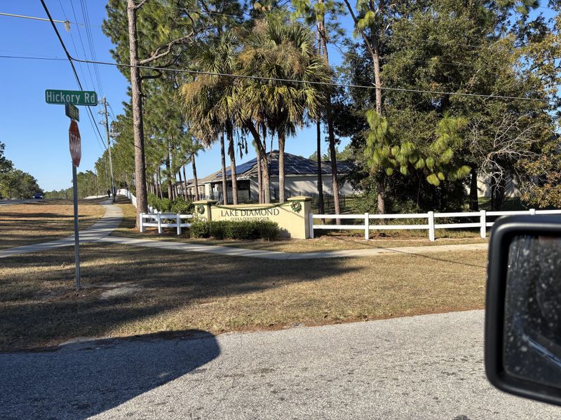 A serene entrance with lush trees and a welcoming sign at Lake Diamond by D.R. Horton in Ocala, FL.