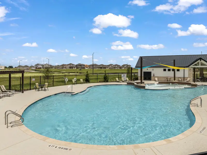 A swimming pool with a fence and buildings in the background.
