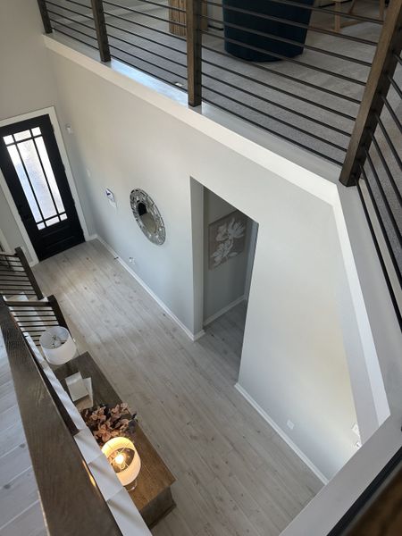 A sleek foyer with light wood floors, modern railing, and stylish decor accents for a welcoming entrance.