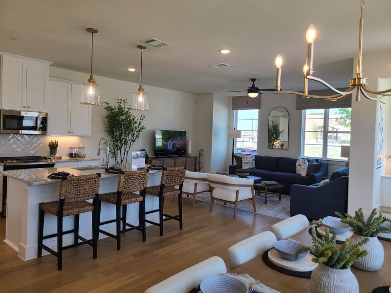 A modern open-concept living space with chic lighting, hardwood floors, and a kitchen island with woven barstools. A modern open-concept living space with chic lighting, hardwood floors, and a kitchen island with woven barstools.