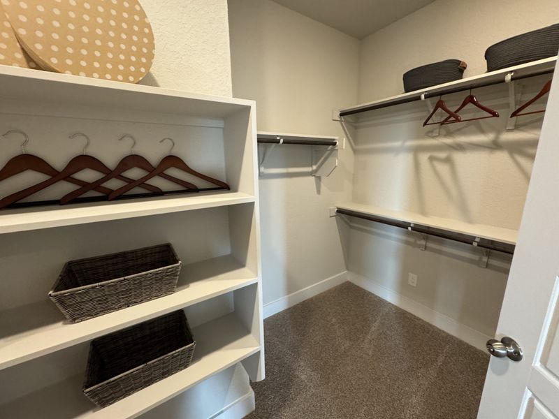 A spacious walk-in closet featuring wooden shelves, hangers, and wicker baskets for stylish storage solutions. A spacious walk-in closet featuring wooden shelves, hangers, and wicker baskets for stylish storage solutions.