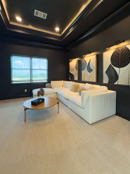 A cozy room with a plush white sofa, elegant artwork, and soft lighting on dark walls. A cozy room with a plush white sofa, elegant artwork, and soft lighting on dark walls.