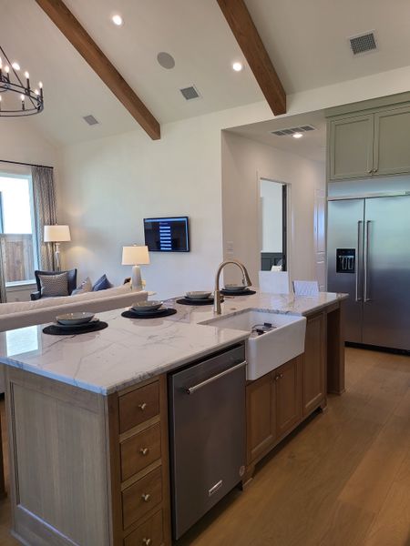 A modern kitchen with a marble island, farmhouse sink, and exposed beams creating a cozy yet elegant atmosphere. A modern kitchen with a marble island, farmhouse sink, and exposed beams creating a cozy yet elegant atmosphere.