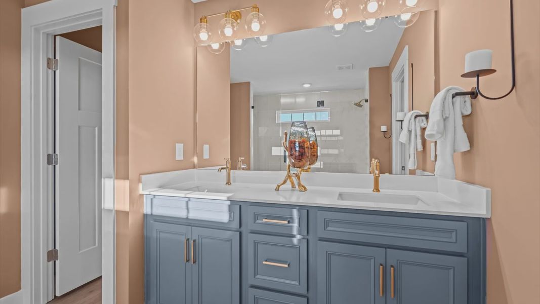 Stunning blue cabinetry with gold accents in primary bath at Mulberry Estates by DRB Homes in Simpsonville, South Carolina