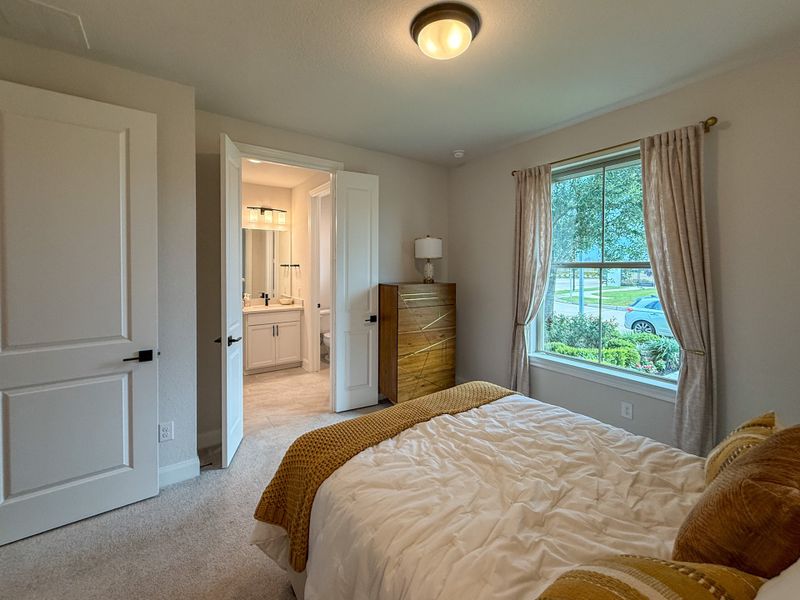 A cozy bedroom with soft lighting, modern furnishings, and a view into a stylish en-suite bathroom.