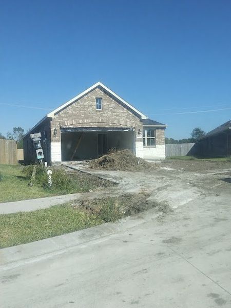 A charming brick home under construction in Cobblestone by Adams Homes, featuring a two-car garage and a spacious driveway.